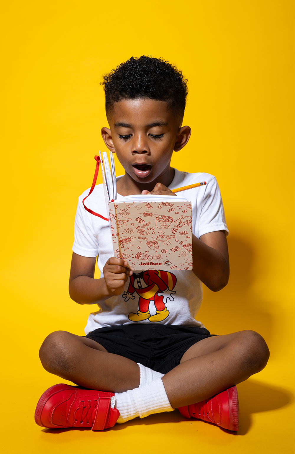 boy sitting down and holding the white Jollibee journal