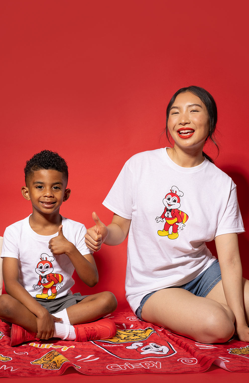 young woman and boy sitting on the Jollibee beach towel with their thumbs up