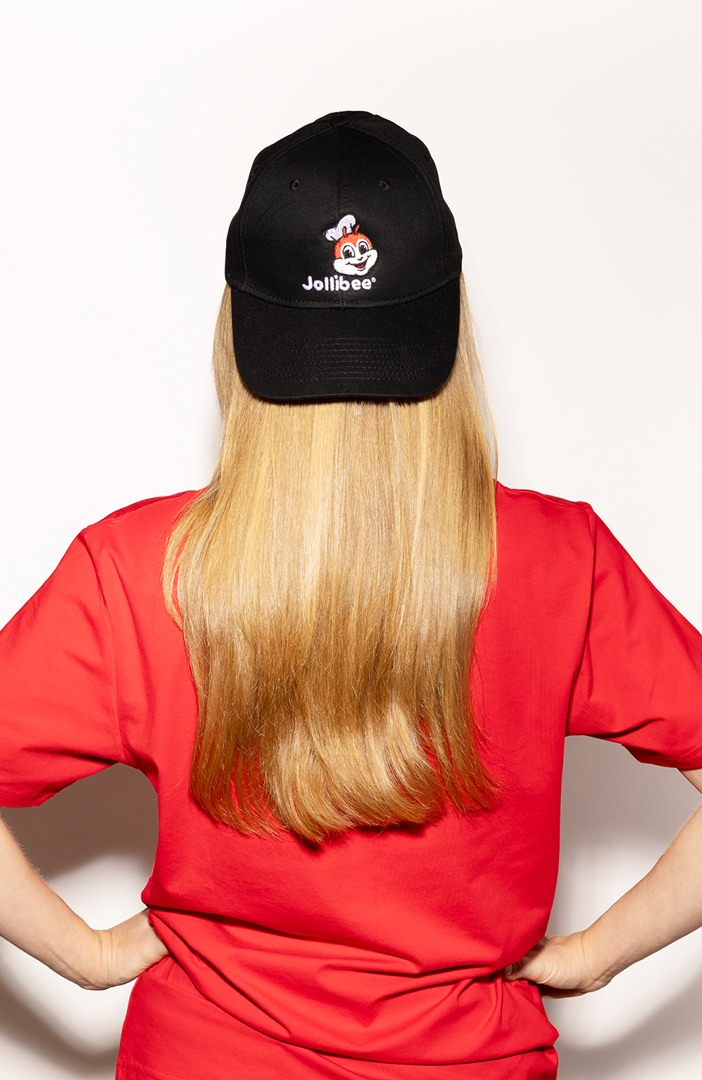 girl with long hair wearing the Jollibee black baseball cap backwards